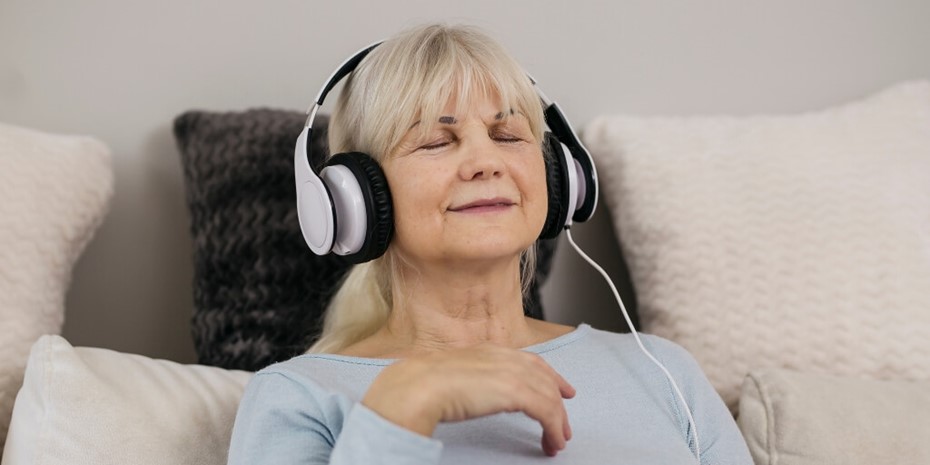 Lady with blonde hair relaxing to music wearing headphones