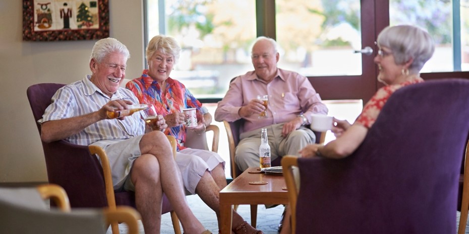 Elderly people drinking and laughing around table